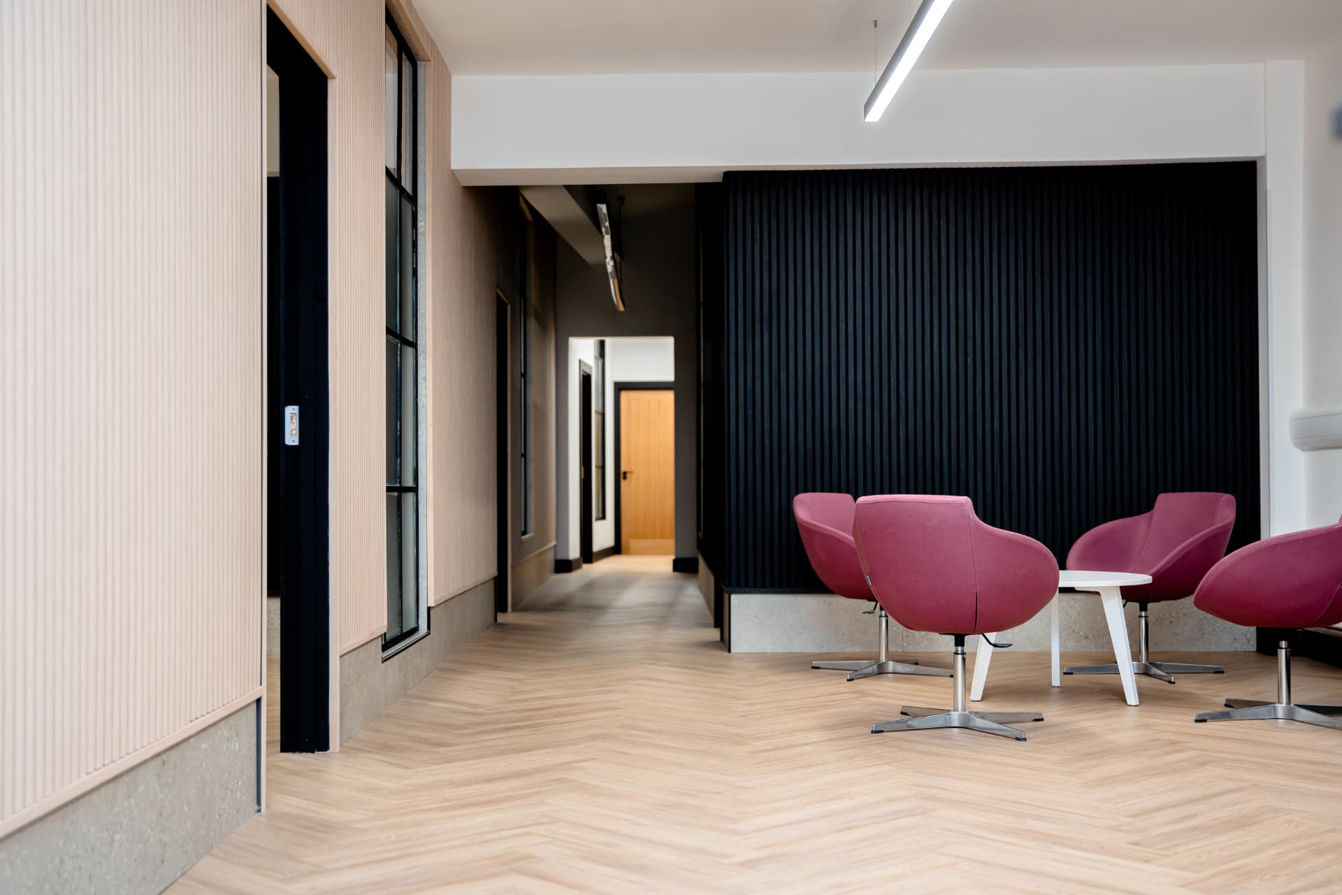 Lounge seating at Patrick's with pink armchairs against a slatted wood wall