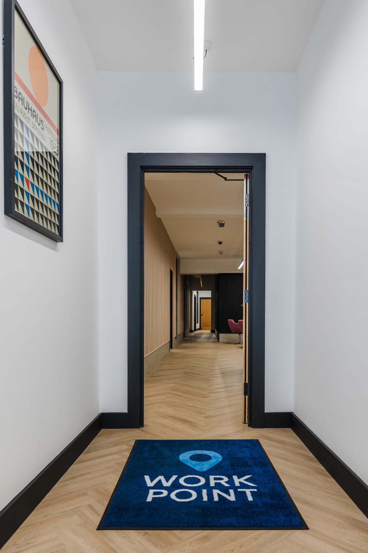 Patrick's entrance with branded floor mat, herringbone flooring and view down the corridor