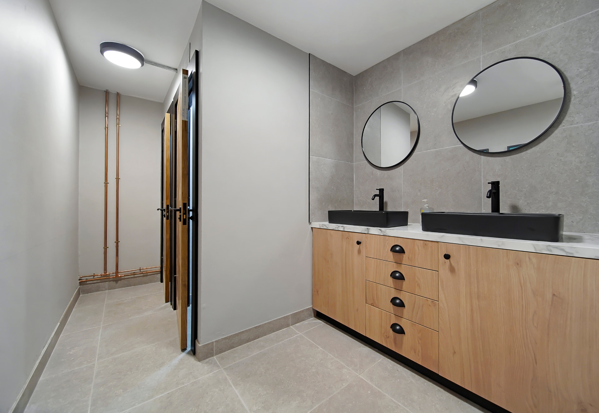 Ladies washroom at Patrick's with twin black basins, round mirrors and oak vanity units