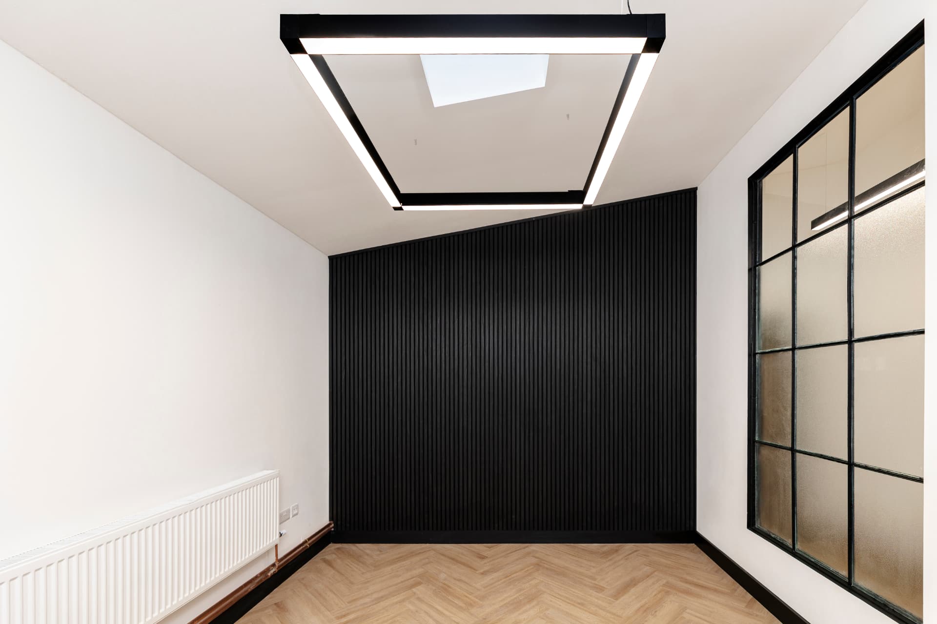 Small private room at Workpoint with black slatted feature wall, feature ceiling lighting and herringbone flooring